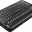 Photo showing an angled perspective view of the Optima Braille Display with an integrated QWERTY keyboard. Shows the words "Optima" in braille on the braille display. The picture shows the QWERTY keyboard on top of the unit, along with cursor routing buttons and rocker keys at the end of the display. On the left side is an audio jack and, a USB C port for charging.