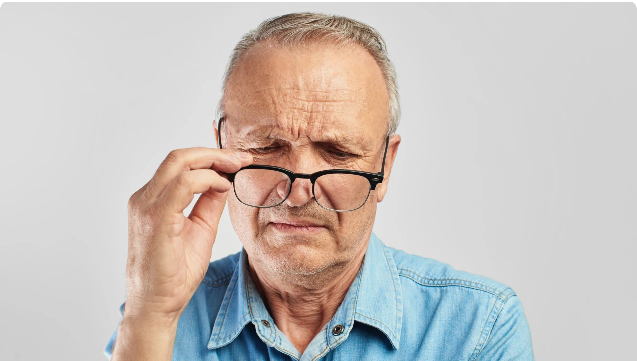 An elderly man adjusting his glasses to improve vision
